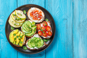 Different types of bruschetta with feta cheese and ricotta on a blue background.