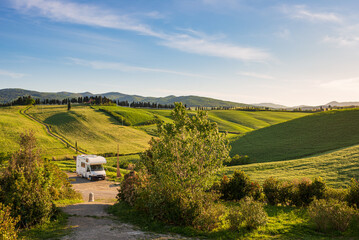 Camper van in unique green landscape, vanlife in Tuscany, Italy. Scenic dramatic sky and sunset...