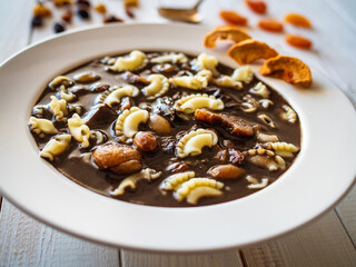 Blood soup with offal and sun dried fruits on wooden table