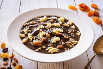 Blood soup with offal and sun dried fruits on wooden table