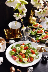 Easter breakfast with fresh salad and eggs on black table