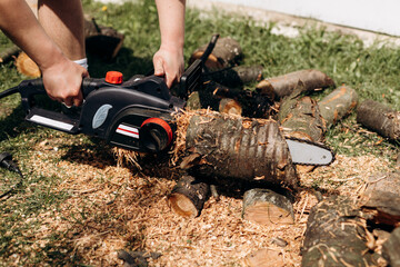 Woodcutter saws tree with chainsaw on sawmill