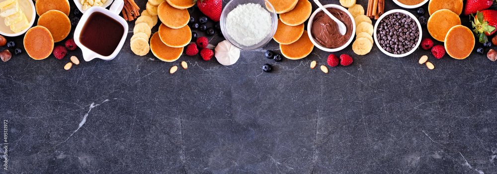 Poster breakfast or brunch pancake buffet top border. above view on a dark stone banner background. mini pa