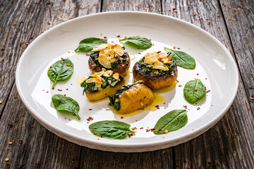 Stuffed white mushrooms with mozzarella, spinach and almonds on wooden table
