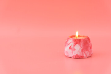 One candle burns pink on a pink background. Concept memory, meditation, spa