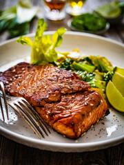 Fried teriyaki salmon steak with pak choi and lime on wooden table

