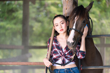 Young adult Asian woman fashion in natural environment. woman enjoying hug a horse in countryside. Cheerful cute model in western style. Cowboy girl.