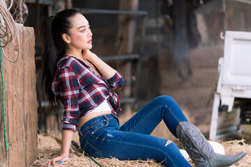 Young adult Asian woman fashion in natural environment. Beautiful cowgirl in the stable. Cheerful...