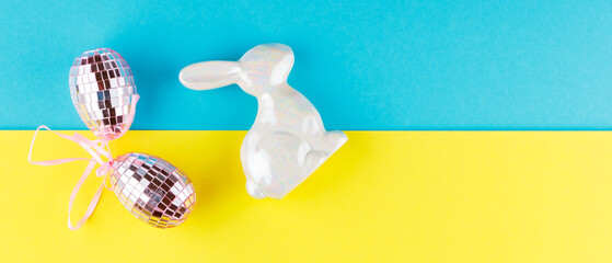 Happy Easter. Easter mirror eggs and holographic bunny on a blue-yellow background. Creative concept of Ukrainian Easter. Top view. Copy space