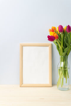 bouquet of colorful tulips in a vase, wooden frame for copy space  on wooden in blue background. Vertical frame.