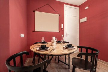 Apartment with round wooden dining table, food service, black chairs, white door and red walls