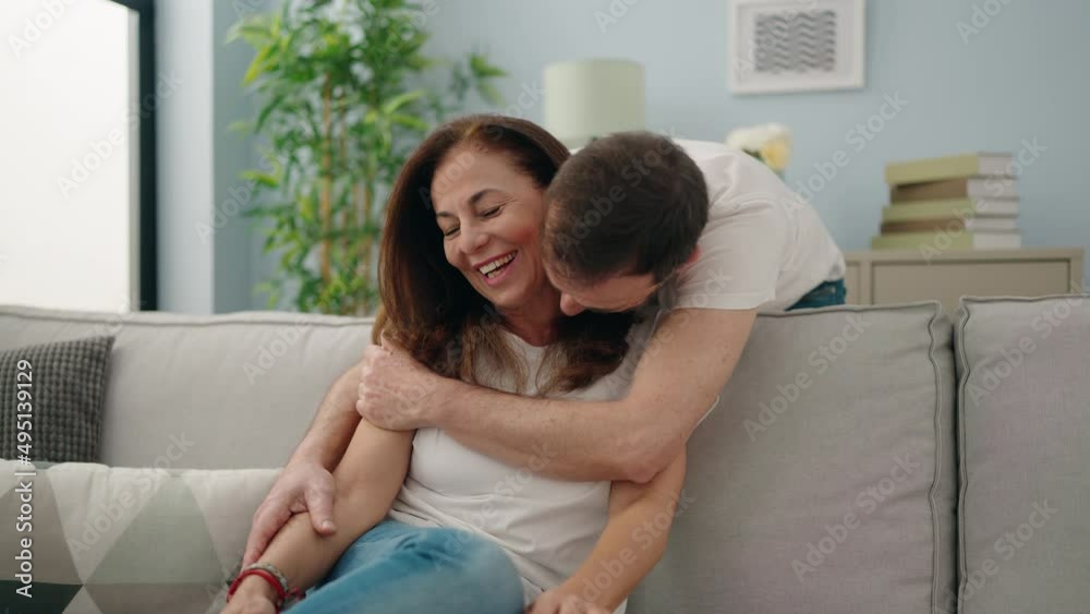 Poster Man and woman couple hugging each other sitting on sofa at home