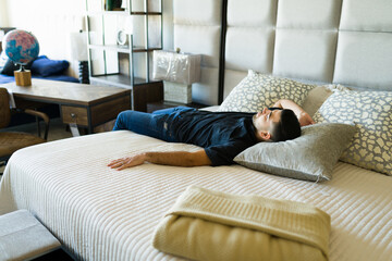 Relaxed man trying a new bed at the store