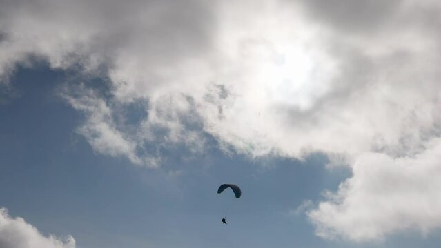 Paragliding adventure sport against bright sun on cloudy sky