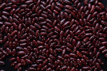 Background of grains of beans laying on a table to inspect bite marks caused by pests destroying pea seeds being prepared for planting. Organic red bean seeds destroyed by insect pests