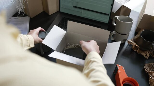 Closeup view of female online store small business owner seller entrepreneur packing package post shipping box preparing delivery parcel on table. Ecommerce dropshipping shipment service concept.