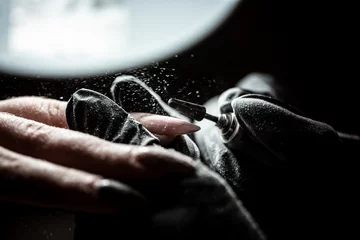 Foto op Plexiglas De meester gebruikt een elektrische machine om de nagellak te verwijderen tijdens manicure in de salon. Hardwarematige manicure. © Надія Коваль