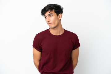 Young Argentinian man isolated on white background making doubts gesture looking side