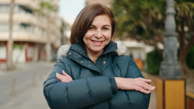 Middle age woman smiling confident standing with arms crossed gesture at street