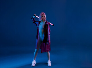 Fototapeta premium Woman in futuristic costume. Female in modern VR glasses interacting with network while having virtual reality experience. Augmented reality game, future technology, AI concept. VR. Neon violet light.