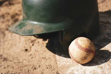 Baseball and batting helmet on ball field - Powered by Adobe
