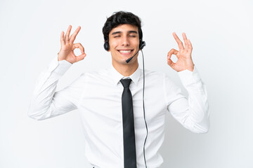 Telemarketer man working with a headset isolated on white background in zen pose