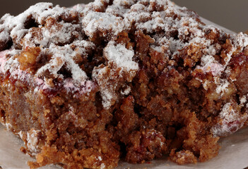 close up, macro shot of a piece of rasberry carrot crumble cake sprinkled with powdered sugar, the inside clearly visible after having been cut into