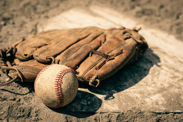 Baseball and mitt on home plate of ball field