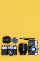 Photographer's equipment. Cameras, lenses and accessories on a yellow background, vertical photo. copy space