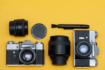 Photographer's workplace, cameras, lenses, accessories on a yellow background close up