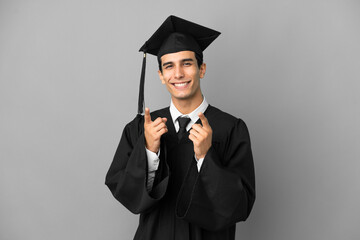 Young Argentinian university graduate isolated on grey background pointing to the front and smiling