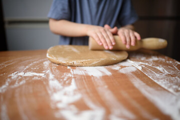 The child rolls out the dough for cookies