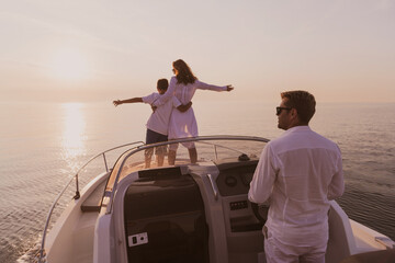 Fototapeta premium A senior couple in casual outfits with their son enjoy while riding a boat at sea at sunset. The concept of a happy family. Selective focus 
