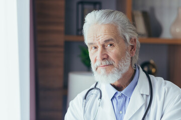 photo close-up portrait of a senior and experienced doctor, gray-haired man looking into the...