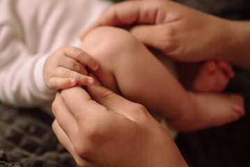 Legs and arms of a newborn and mother's hands