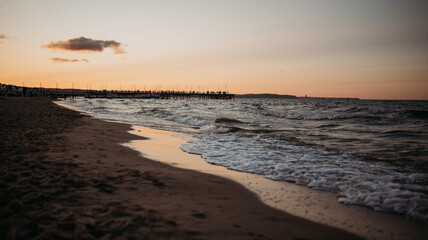 Fototapeta na wymiar Sea, pier and waves at sunset