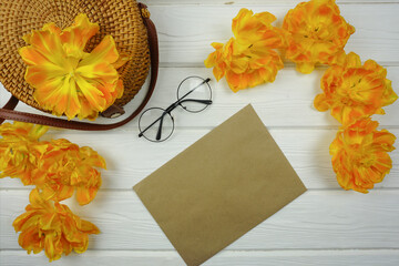 On the wooden table there is a craft envelope with a letter and yellow tulips
