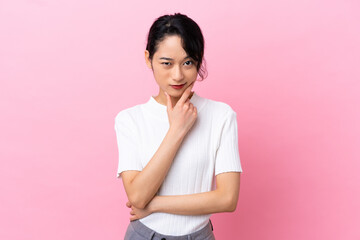 Obraz premium Young Vietnamese woman isolated on pink background thinking