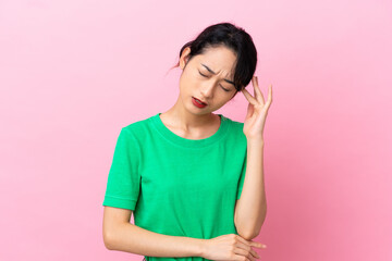 Young Vietnamese woman isolated on pink background with headache