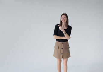 Fototapeta premium Portrait of a brunette pointing her fingers to the side on a white background