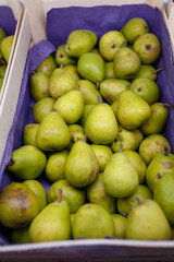 Green pears in box in grocery department of supermarket, store, shop, shopping center. Sweet summer fruit Close up vertical shot
