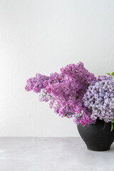 Fresh beautiful bouquet of lilac in a clay pot on a table, part of a home spring interior