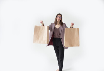 Smiling young shopaholic girl with brown bags on a white background