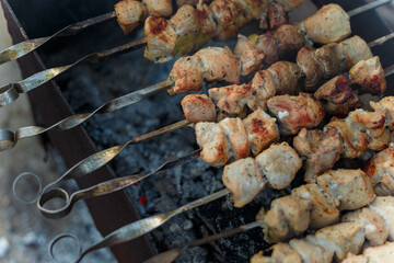 marinaded pork meat pieces on skewers frying over bonfire. Kebab or traditional shashlik cooking with lot of smoke