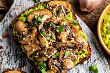 Toast avocado, mushrooms and microgreen whole grain sandwich. Decorated with sesame. Vegetarian food. Vegan menu. Delicious breakfast or snack, Clean eating, dieting, vegan food concept. top view