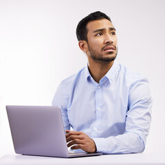 Feeling a bit fearful of the future. Studio shot of a young businessman looking worried while using a laptop against a white background.