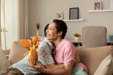 Happy Easter! Woman hugging boyfriend with golden easter egg in the hands.