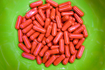 Pills against greed brown color in a green plate