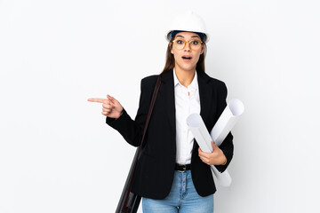 Young architect caucasian woman with helmet and holding blueprints over isolated background surprised and pointing finger to the side