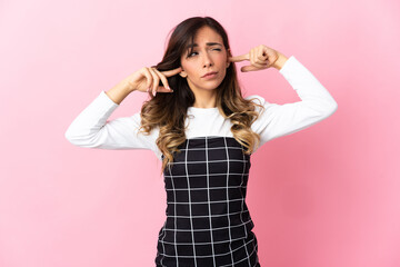 Young caucasian woman isolated on pink background frustrated and covering ears